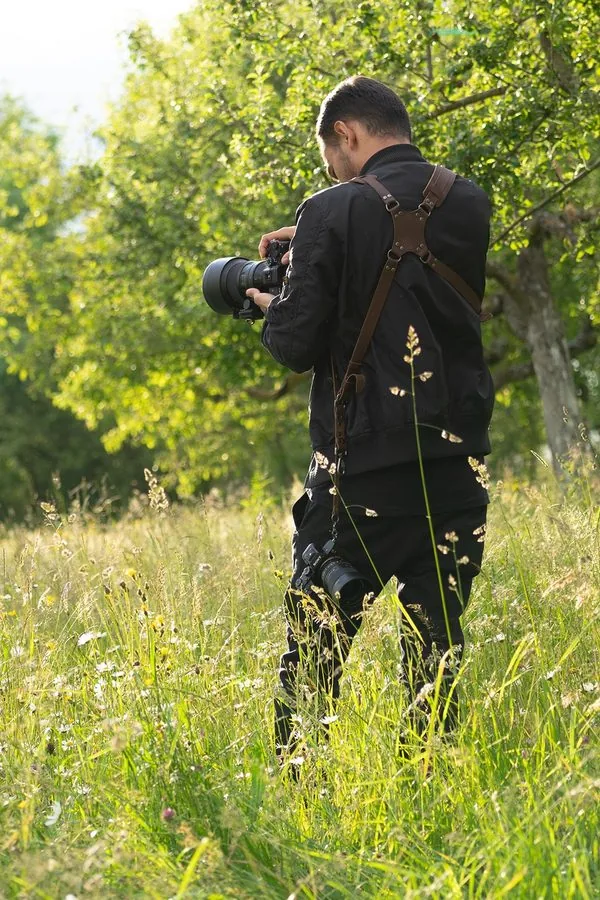 Julian Ahmed fotografiert mit zwei Kameras in einer Sommerwiese